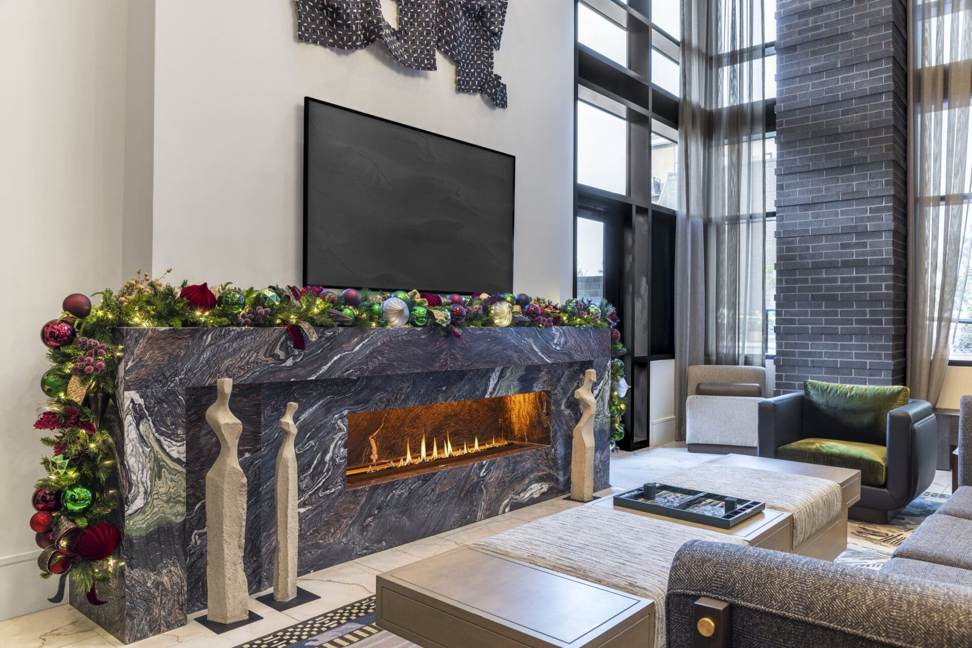Luxury modern Christmas living room decor featuring warm metallic tree ornaments and a cozy fireplace setting by Baker Design Group.